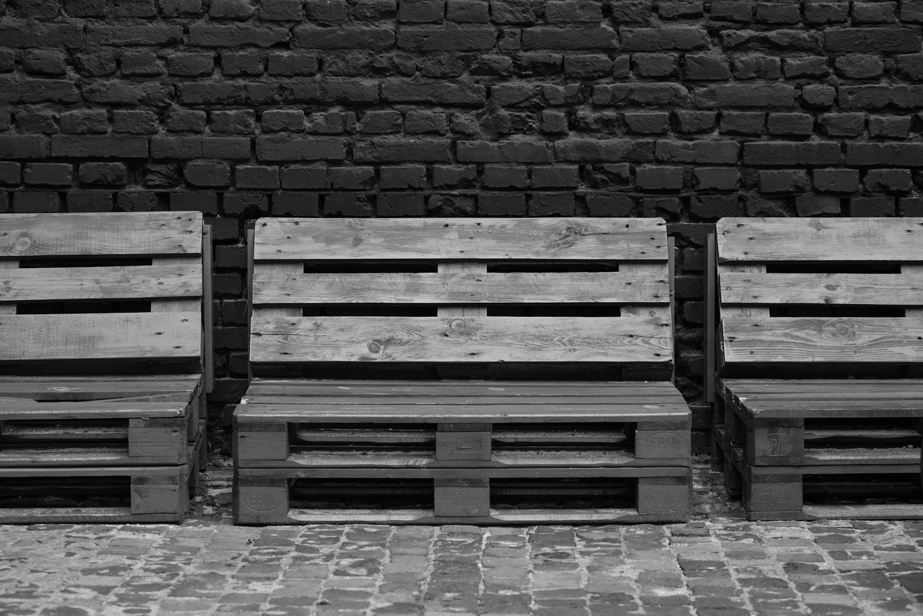 Ławki z palet przed ceglaną ścianą w minimalistycznym stylu