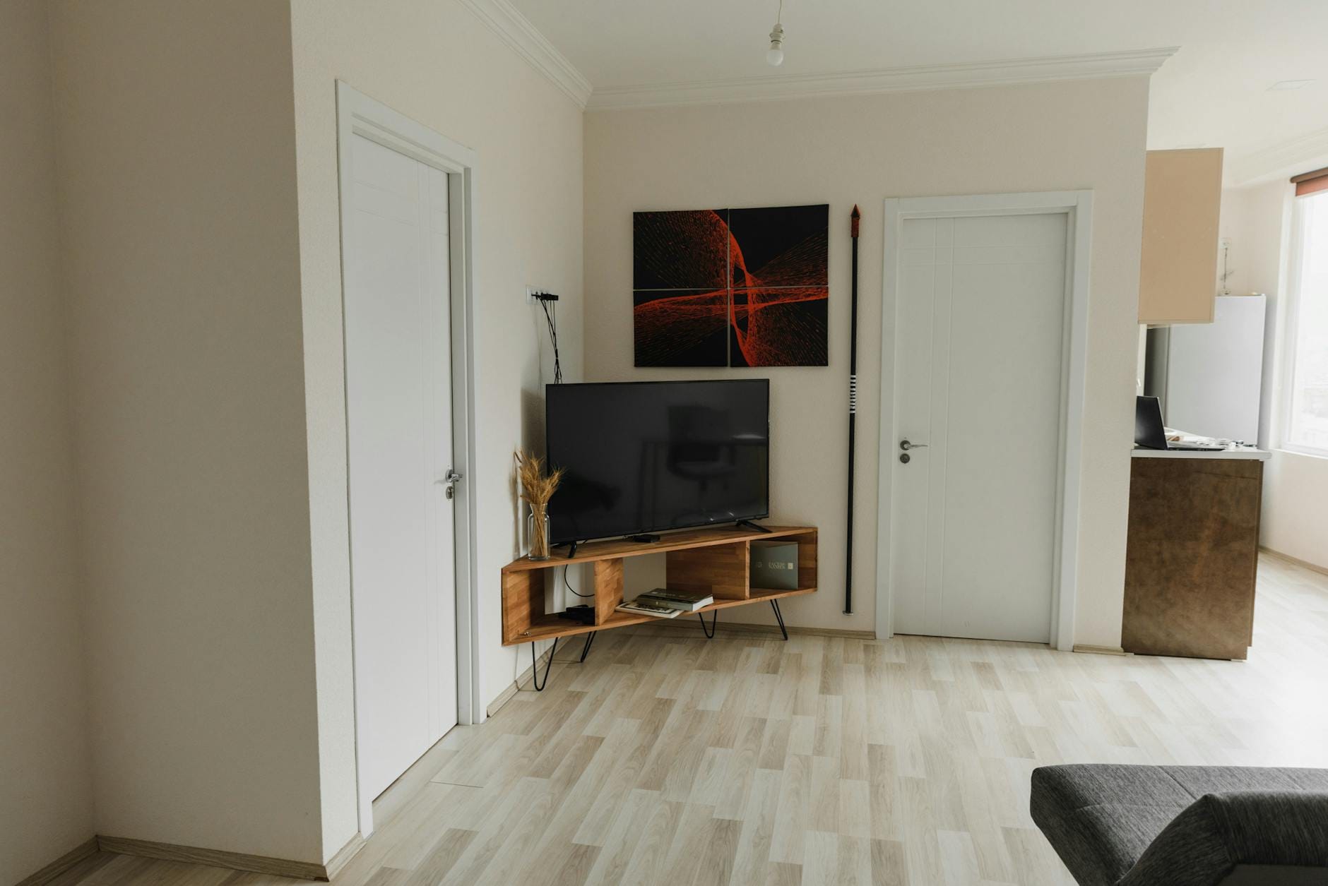 Minimalistyczny salon z telewizorem na ścianie i drewnianą podłogą